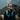 A woman wearing Julbo-usa Monterosa 2 sunglasses with removable side shields and outdoor gear smiles in front of a forested mountain landscape.