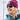 Wearing a maroon beanie, the person smiles outdoors in a blue jacket and Julbo-usa Monterosa 2 sunglasses with removable side shields—ideal for adventure seekers.