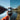 A hand holds a smartphone in front of a mountain lake; the image is split vertically to show two different color tones for comparison.