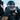 A person wearing a black helmet, ski goggles, and winter jacket adjusts their goggles outdoors in a snowy environment.