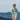 Woman in a light green jacket and sunglasses running with mountains in the background
