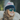 A person with wavy hair wearing Julbo Eyewear's Slack Cover reflective polarized sunglasses, a striped beanie, and a fur-collared coat is smiling outdoors.