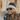 A woman wearing Julbo Eyewear’s Ward retro sunglasses, a winter coat, and a knit hat smiles outdoors in natural light.