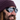 Close-up of a smiling person wearing a knit beanie and reflective sunglasses with a snowy landscape seen in the reflection of the lenses.