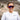 A woman wearing Julbo Eyewear Faster sunglasses and a white Terrex shirt smiles outdoors against a rocky landscape, showcasing high-performance sports eyewear designed for any adventure.