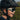 A young child wearing a black cycling helmet and Julbo-usa Fury Mini Kids sunglasses smiles outdoors with a blurred green background.