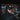 A man wearing a black winter jacket, a hat, and Julbo Eyewear Fury Black Series sunglasses stands before a wall adorned with colorful stickers.