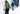 Two skiers wearing helmets and goggles walk through a snowy, icy passage with ski poles in hand.