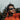 A man wearing Julbo Eyewear Montebianco 2.0 RX sunglasses stands outdoors in a mountainous, forested area, dressed in an orange jacket.