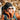 A woman in a black headband and orange jacket with a backpack, wearing Julbo Eyewear's Monterosa 2.0 RX sunglasses with REACTIV photochromic lenses, stands outdoors in the mountains for optimal performance.