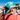 Wearing a floral cap and Julbo Eyewear sunglasses secured by a Neoprene Sunglass Strap, a person drinks from a can outdoors with snowy trees blurred in the background. #color_julbo-neoprene-sunglass-strap-blue-lightning