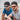 Two men in black caps and casual shirts sit on sand outdoors, both wearing Julbo Eyewear Renegade RX stylish prescription sunglasses with Spectron Rx polycarbonate lenses as they face the camera.