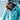 A man wearing a blue The North Face jacket, helmet, sunglasses, and backpack stands outdoors in a snowy mountain environment.