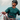Wearing the Julbo-usa Shield mountain sunglasses and a teal shirt, a helmeted individual holds climbing ropes and looks upward, appearing ready for rock climbing.