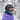 Person wearing a black helmet, Julbo Eyewear Shield RX photochromic lenses, teal neck gaiter, and purple jacket stands in a snowy forest.