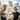 Two men in casual clothing wear Julbo Eyewear's The Streets sunglasses outdoors by a marina, smiling with tall buildings and boats in the background.