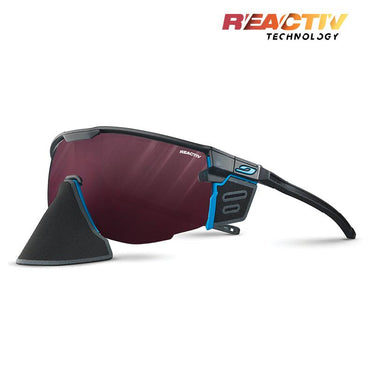 The Julbo-usa Ultimate Cover sports sunglasses feature a black and blue frame, red-tinted panoramic lens, detachable black nose guard, and REACTIV Technology branding for advanced sun protection. #color_black-blue-with-reactiv-0-4-high-contrast-lens