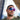 A man with short hair and a trimmed beard wears Julbo Eyewear Ultimate RX prescription sports glasses with REACTIV photochromic lenses and a green shirt, standing outdoors near modern glass buildings.