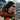 Smiling outdoors in a mountainous landscape, a person wears a headband, an orange jacket, and Julbo-usa Ultimate performance sunglasses.