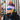 A person in a purple hat, winter jacket, and blue Julbo Eyewear Whoops sunglasses stands before a ski rack covered in stickers.