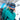A person in a teal jacket, helmet, and blue Julbo Eyewear Whoops sunglasses is outdoors in a snowy mountain area.