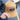 A person holds a tan Julbo Eyewear Woodsman Hat, an earflap hat ideal for cold weather with a black JULBO patch, while standing on an outdoor path. #color_julbo-woodsman-hat-tan