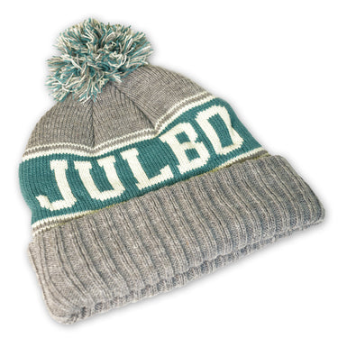 The Julbo Eyewear Classic Pom Beanie is a gray winter hat with green and white stripes, a pom-pom, and "JULBO" knitted on the front—perfect for staying warm in Alpine style. #color_julbo-classic-pom-beanie-grey-green-and-lime