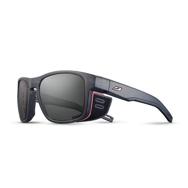 Julbo Eyewear's Shield M RX sports sunglasses feature a matte black frame with dark lenses, red accents, removable side shields, and a fabric temple strap. Compatible with REACTIV photochromic Rx lenses for custom prescriptions. #color_translucent-gray-/-pink