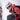 A close-up lifestyle shot of a person wearing a white and orange Petzl helmet, blue mirrored ski goggles, a red ski jacket, and a black backpack against a bright, snowy white background.