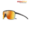 Julbo Eyewear Frequency sunglasses with a black shield-style frame, orange photochromic vented lens, shown at an angle on white. REACTIV PHOTOCHROMIC logo appears in the top right corner. #color_black-gray-with-reactiv-1-3-light-amplifier-lens
