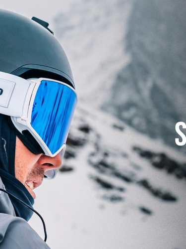A skier wearing a black helmet and white Julbo ski goggles stands outdoors; promotional text advertises the Tim McChesney Signature Ski Goggle.