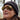 A person wearing a dark knit beanie and reflective sunglasses is outdoors, with trees reflected in the lenses.