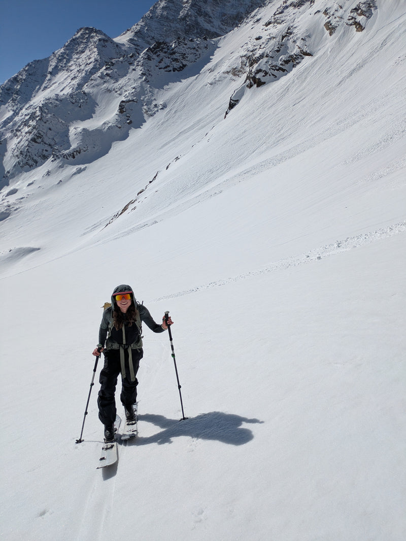 Woman skinning up a mountain while wearing Julbo Frequency sunglasses