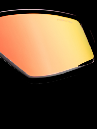 A close-up of the orange-yellow tinted lens of a pair of sunglasses against a black background.