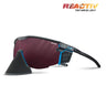 The Julbo-usa Ultimate Cover sports sunglasses feature a black and blue frame, red-tinted panoramic lens, detachable black nose guard, and REACTIV Technology branding for advanced sun protection. #color_black-blue-with-reactiv-0-4-high-contrast-lens