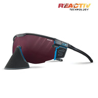 The Julbo-usa Ultimate Cover sports sunglasses feature a black and blue frame, red-tinted panoramic lens, detachable black nose guard, and REACTIV Technology branding for advanced sun protection. #color_black-blue-with-reactiv-0-4-high-contrast-lens
