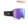 The Julbo USA Razor Edge is a black frameless ski goggle with a wide, mirrored purple REACTIV lens and a black strap featuring a white logo, shown on a white background with "REACTIV TECHNOLOGY" in the top right corner.